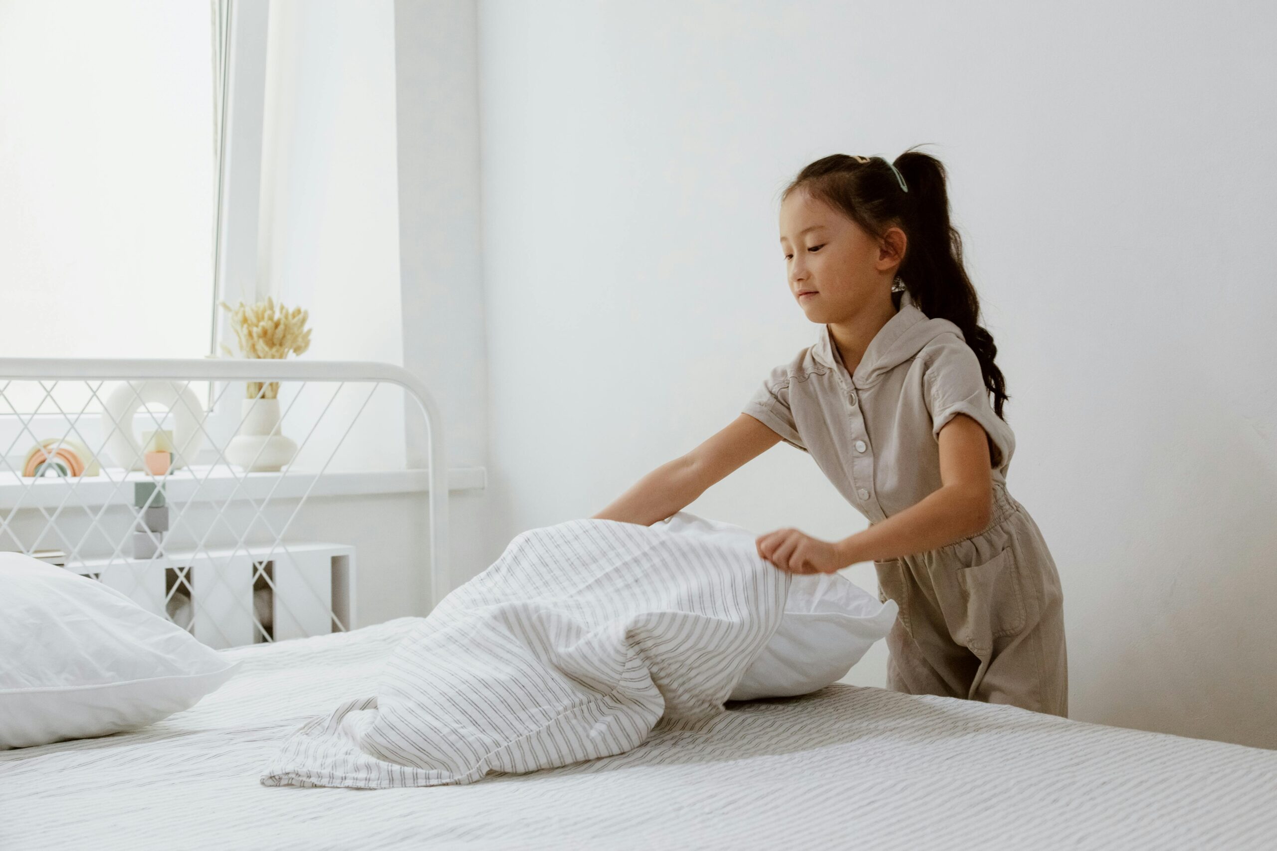 child making bed and learning responsibility